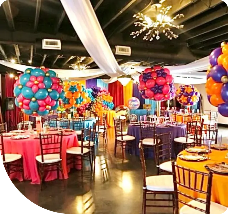 A room filled with tables and chairs covered in balloons.